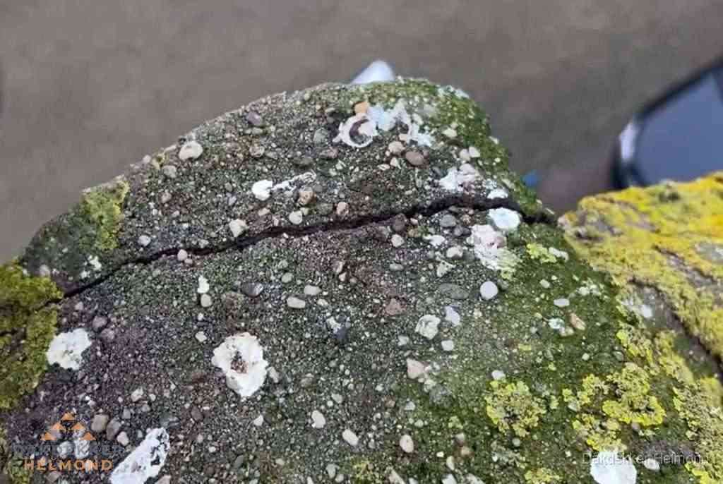 Beschadigde en verweerde nokvorst met scheuren en mos in Helmond