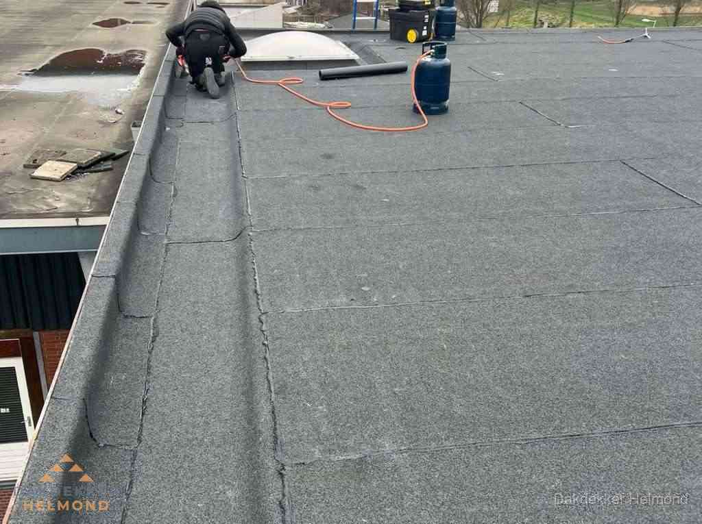 Dakdekker repareert bitumen dakbedekking op groot plat dak in Helmond